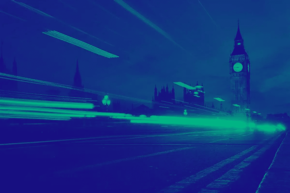 London skyline with Big Ben at night, featuring blue and green light trails from passing traffic.