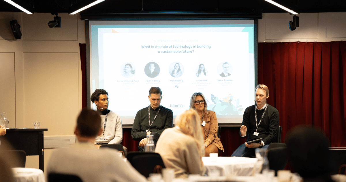 Panel discussion on technology's role in sustainability with four speakers seated in front of presentation screen.